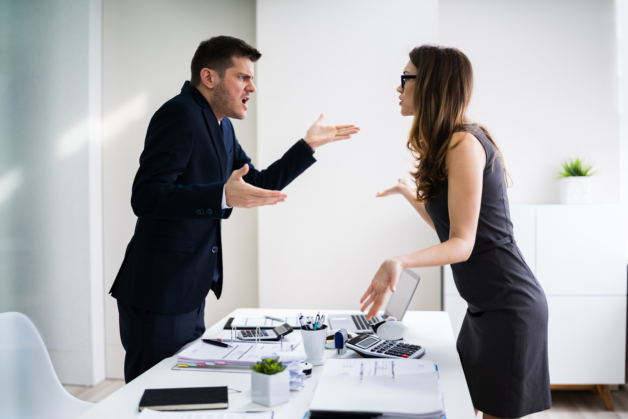 Side View Of Business People Quarreling At Desk In Office